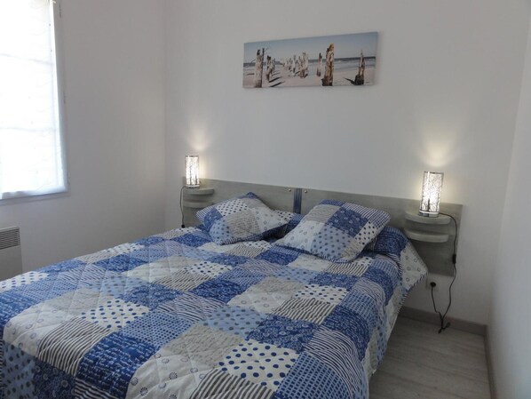 Un dormitorio con una cama, dos lámparas de noche, un cuadro en la pared y una ventana.