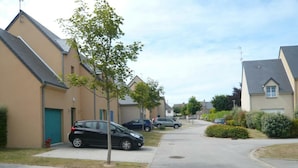 A residential street with houses, parked cars, and a tree-lined sidewalk. - Private Garden in Barfleur - Ground Floor Apartment (Barfleur)