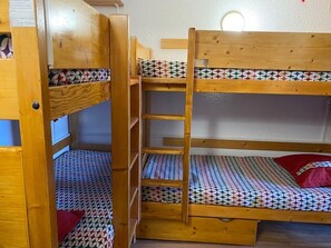 Een slaapkamer met een stapelbed, houten wanden en beddengoed met een patroon.