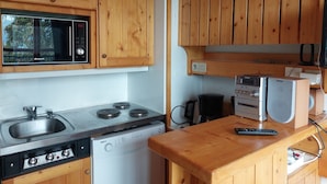 Ett kompakt kök med träskåp, en mikrovågsugn, en spis och en kaffebryggare.