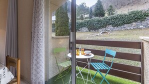 A balcony with a table, chairs, and a view of a garden and hills. - Cozy 1BR Apartment for 4 with Balcony, Near Ski Lift and Amenities in Cauterets (Cauterets)