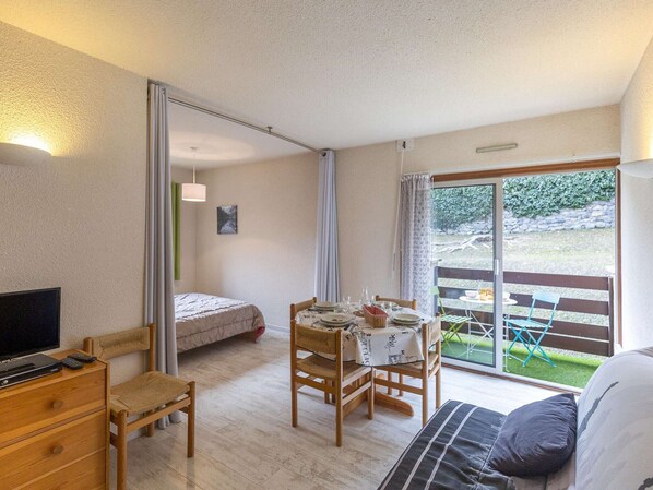 Una habitación con cama, un escritorio con ordenador, una mesa de comedor para dos personas y un sofá.