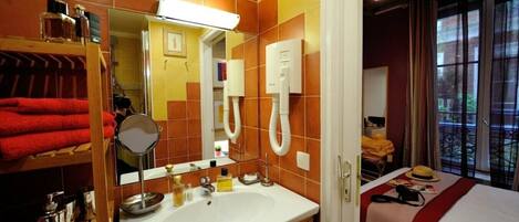 A hotel bathroom with a sink, mirror, and towel rack.