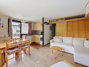 A compact living space with a dining area, kitchenette, and a sofa.