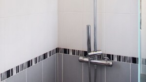En modern dusch med ett justerbart duschmunstycke och ett vertikalt placerat regnduschmunstycke.