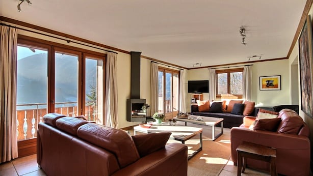 A spacious living room with a brown leather sofa, a black sofa, and a wooden coffee table. There is a TV mounted on the wall and a fireplace. Large windows provide natural light and a view of the outdoors. - CHALET WIFI - SAINT JEAN D'AULPS - 1 PEOPLE - TATOP (Saint-Jean-d´Aulps)
