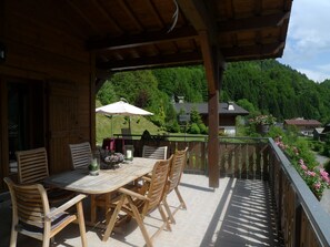 Enjoy a serene view of the surrounding landscape from this outdoor deck with a table and chairs.