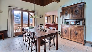 A dining area with a wooden table and chairs, a cabinet with decorative handles, and a view of the outdoors. - CHALET WIFI - SAINT JEAN D'AULPS - 1 PEOPLE - TATOP (Saint-Jean-d´Aulps)