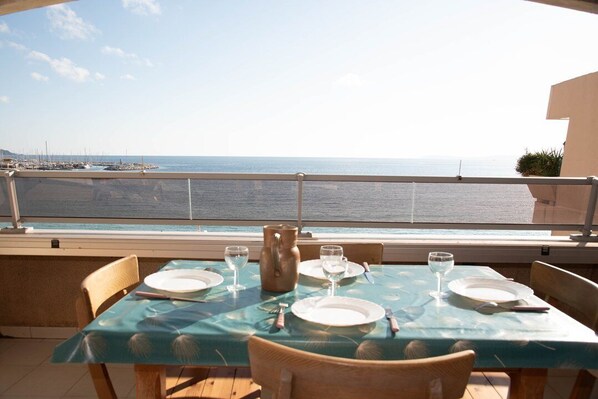 Mesa para dos con vista al mar y barcos al fondo.