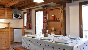 A cozy kitchen with wooden beams, a microwave, a refrigerator, and a dining table set for four. - Traditional chalet for 8 in Méribel, calm and picturesque (Méribel)