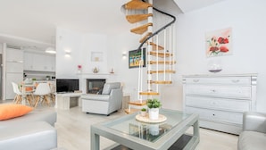 A modern living room with a glass coffee table, a grey sofa, and a staircase with wooden steps. - Piscina, mar y centro – Casa ideal para familias (Empuriabrava)
