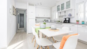 A modern kitchen with white cabinets, a dining table with chairs, and a coffee machine. - Piscina, mar y centro – Casa ideal para familias (Empuriabrava)