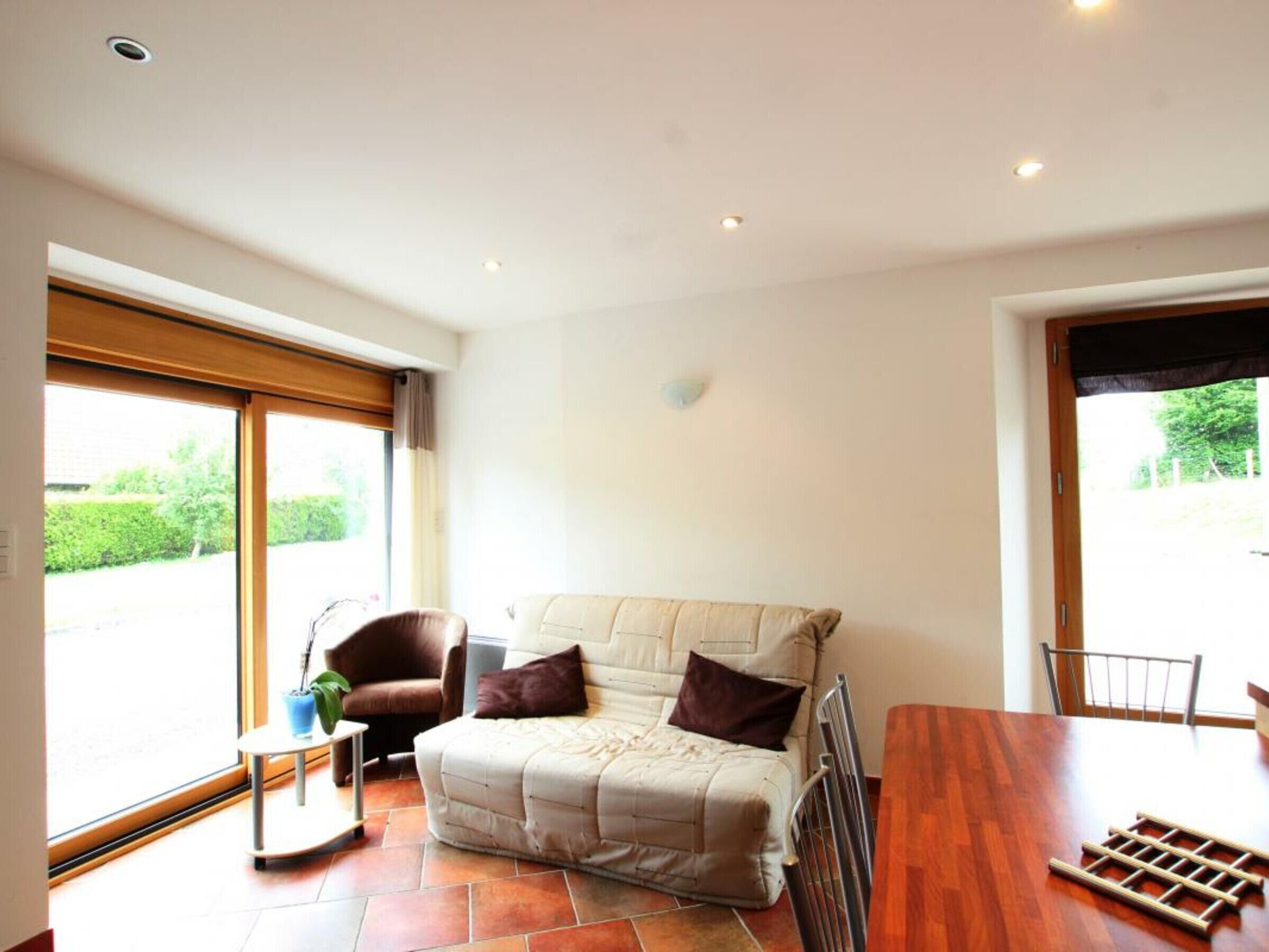 A modern living room with a beige sofa, a brown armchair, and a small table with a plant.