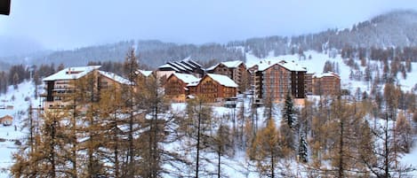 A cluster of log cabins with multiple stories, surrounded by a snowy forest.