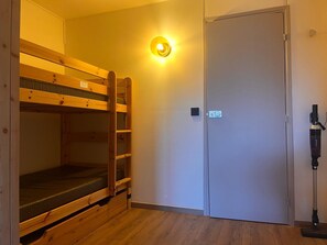 A bunk bed room with a door and a vacuum cleaner.