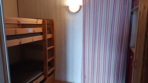 A bunk bed with a headboard, a striped curtain, and a wall-mounted light fixture. - Studio 5 pers, ski-in/ski-out, near shops (Les Arcs 1800)