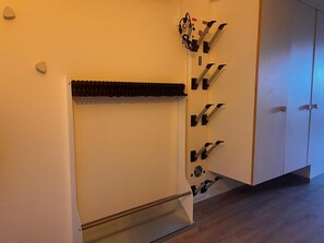 A room with a white wall, a black object mounted on it, and a wooden floor.