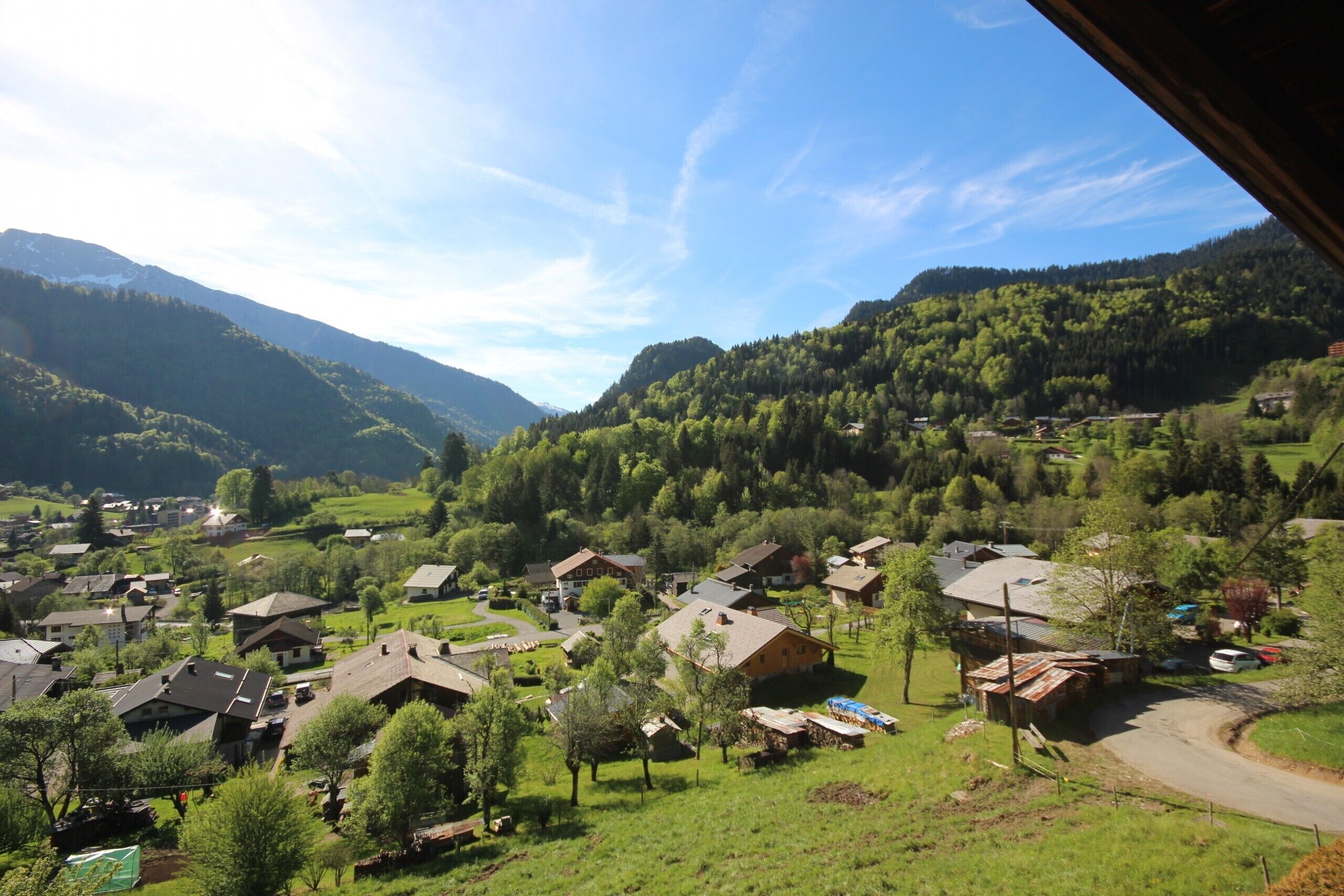 Uma aldeia rural com casas rodeadas por vegetação e montanhas ao fundo.