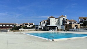 Uma área de piscina com um edifício moderno ao fundo.