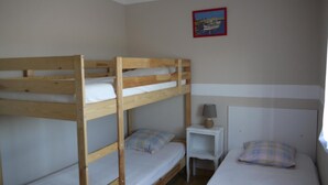 Habitación con literas, una mesita de noche pequeña y una lámpara.