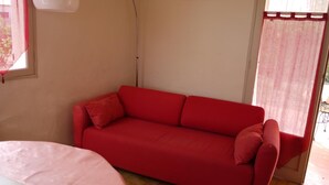Un sofá rojo en una habitación con una ventana y una puerta.