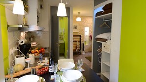 A compact kitchen with a dining area, equipped with a toaster, kettle, and a variety of fruits and vegetables.