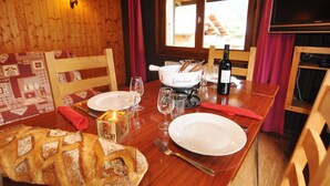 Una mesa de madera con un set de fondue, una botella de vino y platos.