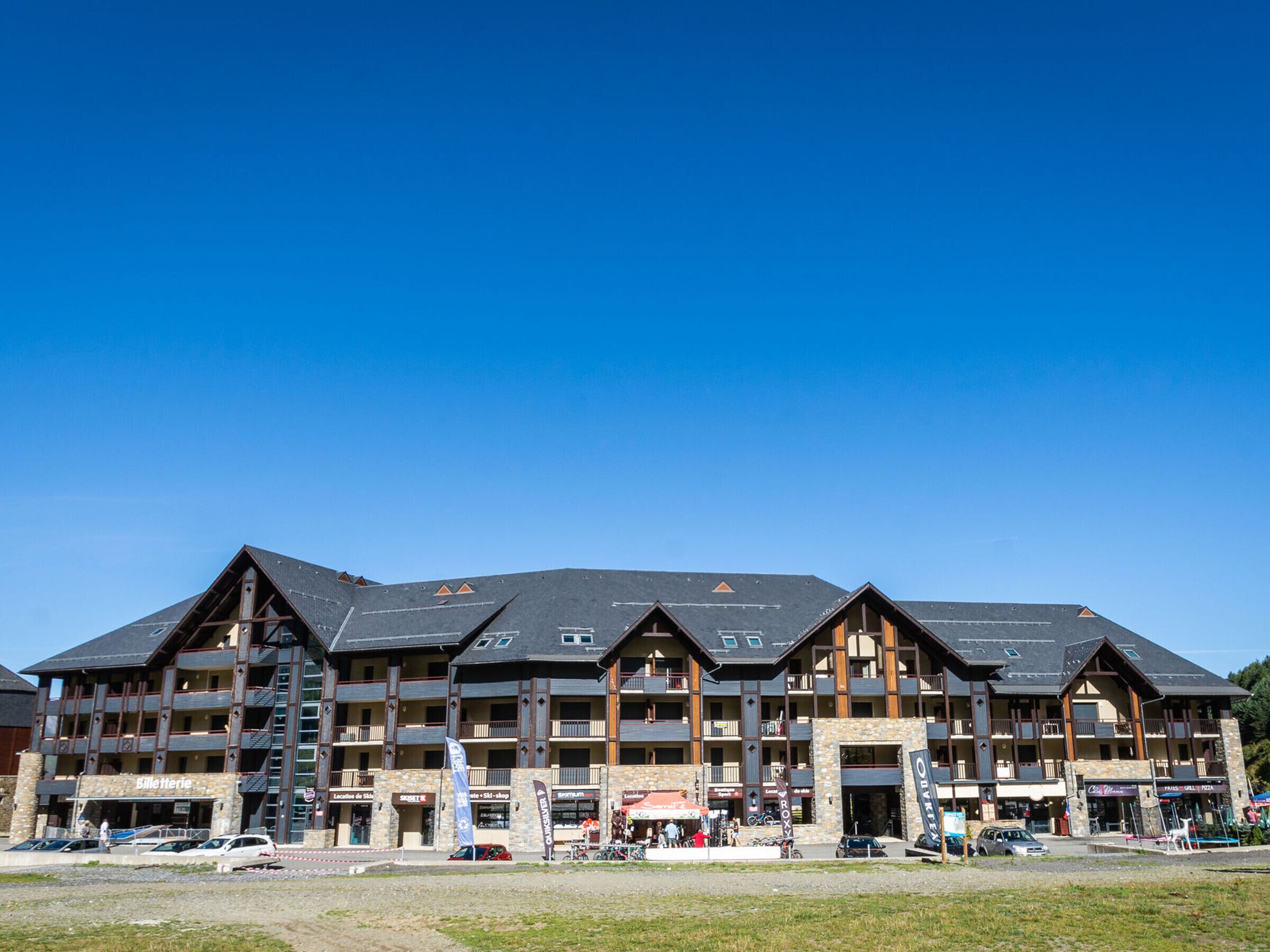 A multi-story hotel with a ski shop, restaurant, and outdoor seating area.