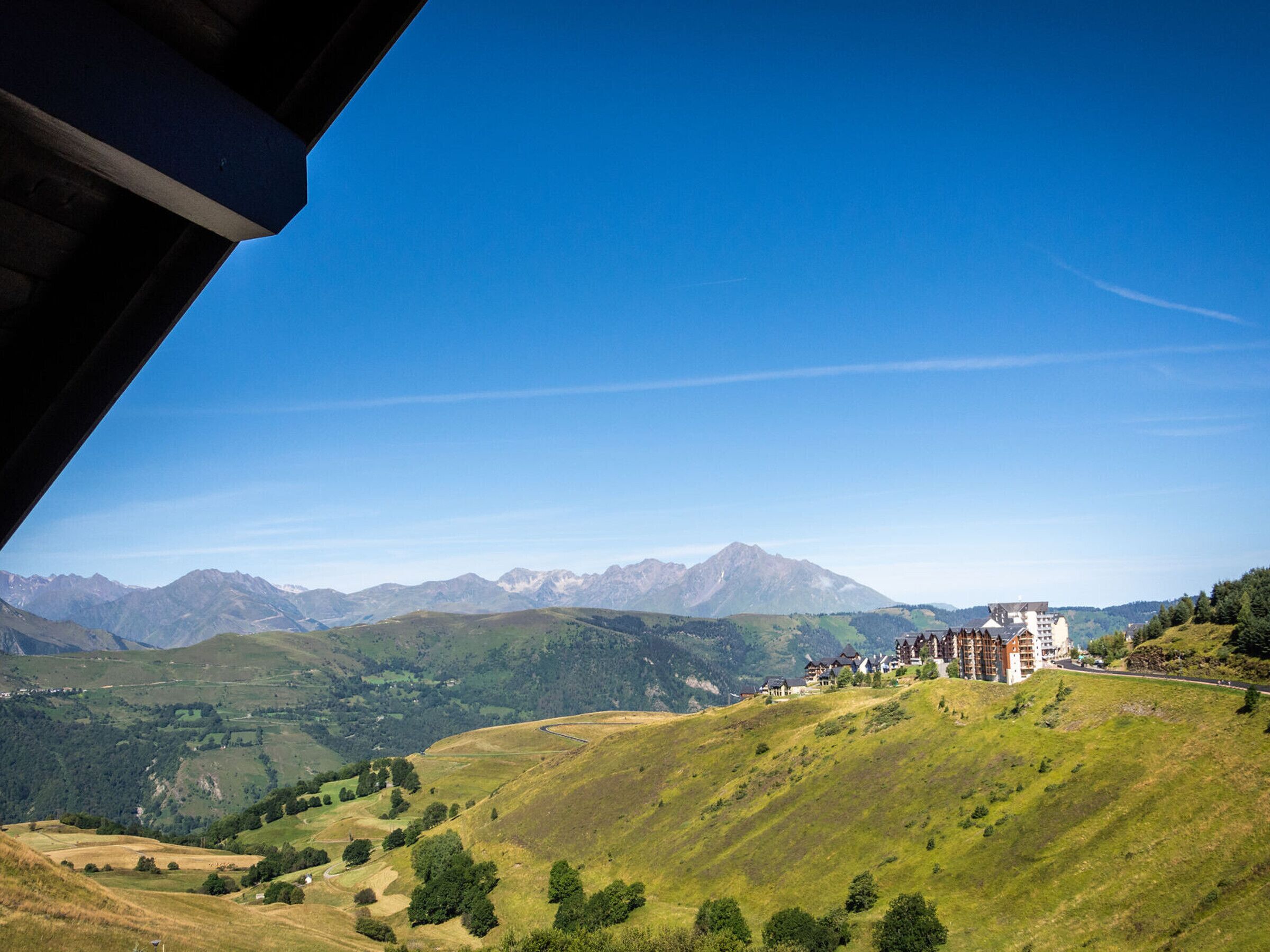 Paisatge de muntanya amb un hotel sobre una vessant.