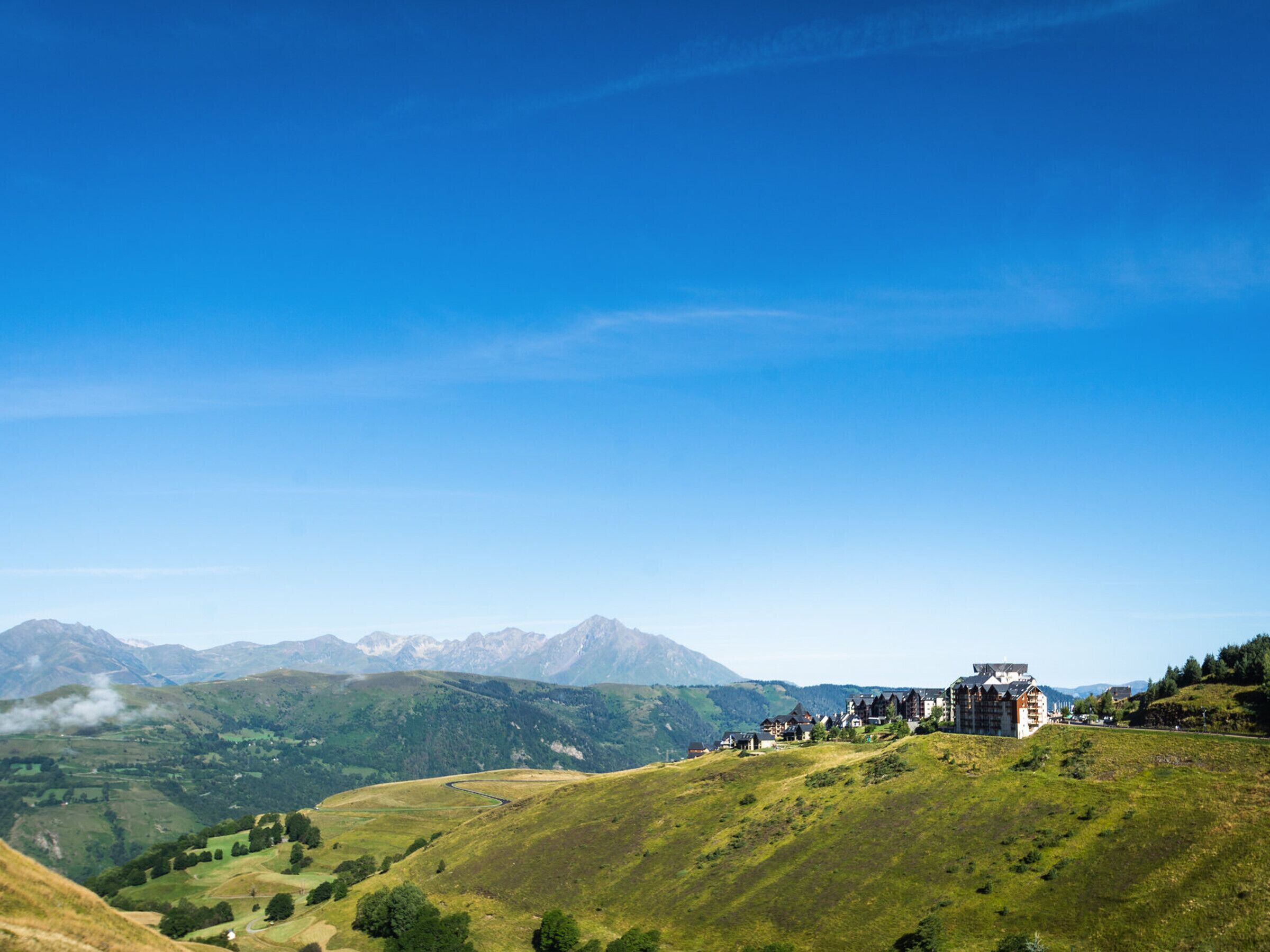 A hotel on a hillside with a view of mountains in the background.