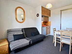 A compact living space with a sofa, a dining table with chairs, a kitchenette, and a mirror on the wall. - Studio for 4 people near slopes - Pets allowed (Chamrousse)