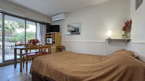 Une chambre d’hôtel avec un lit, un bureau et une chaise. Il y a une fenêtre donnant sur des palmiers.