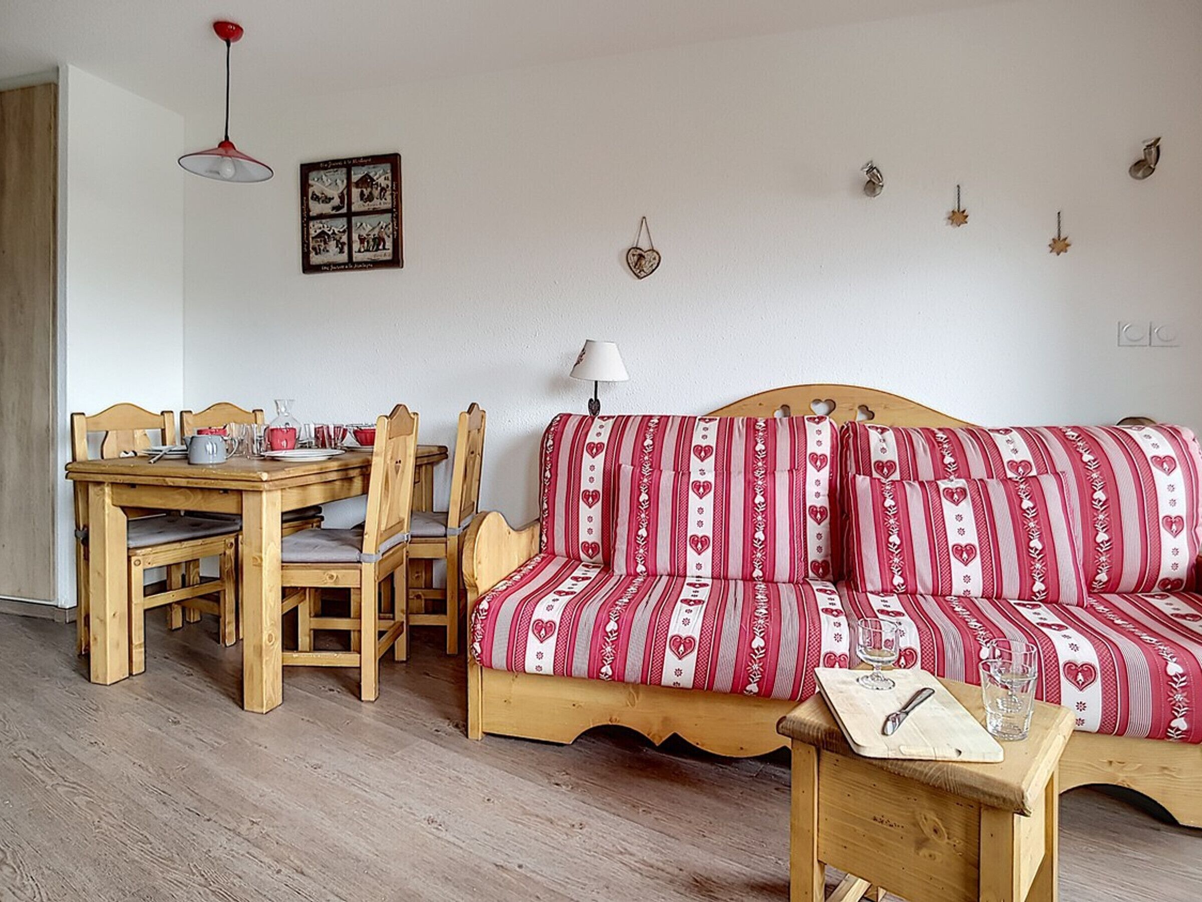 Un salon chaleureux avec un canapé en bois, une table à manger avec des chaises et un plancher en bois.