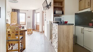 Una cucina compatta con isola centrale, mobili in legno e forno a microonde.