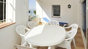 Una mesa y sillas blancas en un balcón con vista al mar.