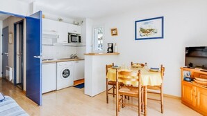 A compact living space with a kitchenette, a dining area, and a TV.