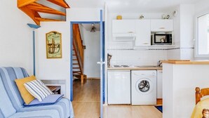 A compact living space with a sofa, a washing machine, a microwave, and a small kitchen area.