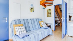 A room with a blue-striped sofa, a small table, and a staircase leading to another room.