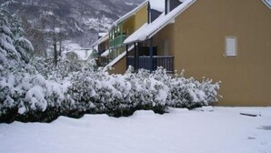 A snow-covered building with a balcony and a mountain backdrop.