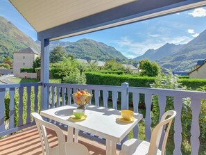 Un balcon avec une table et des chaises, donnant sur un paysage montagneux.