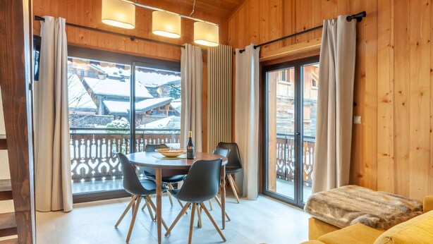 Un interior de madera con comedor, sofá y vistas a través de amplios ventanales.