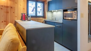 Cocina moderna con una isla central, microondas integrado y armarios oscuros.