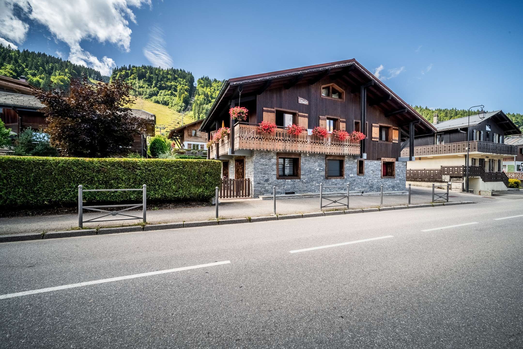 Un edificio in legno di due piani con balconi, facciata in pietra e una vista libera sul paesaggio montuoso circostante.