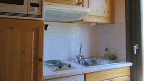 Une cuisine dotée de meubles en bois, d’un four à micro-ondes Bosch, d’un four encastré, d’un évier en acier inoxydable et d’un lave-vaisselle.