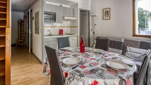 Cucina compatta con forno a microonde, tostapane e lavello. Un tavolo da pranzo con sedie è apparecchiato per quattro persone, e una finestra permette l'ingresso di luce naturale.