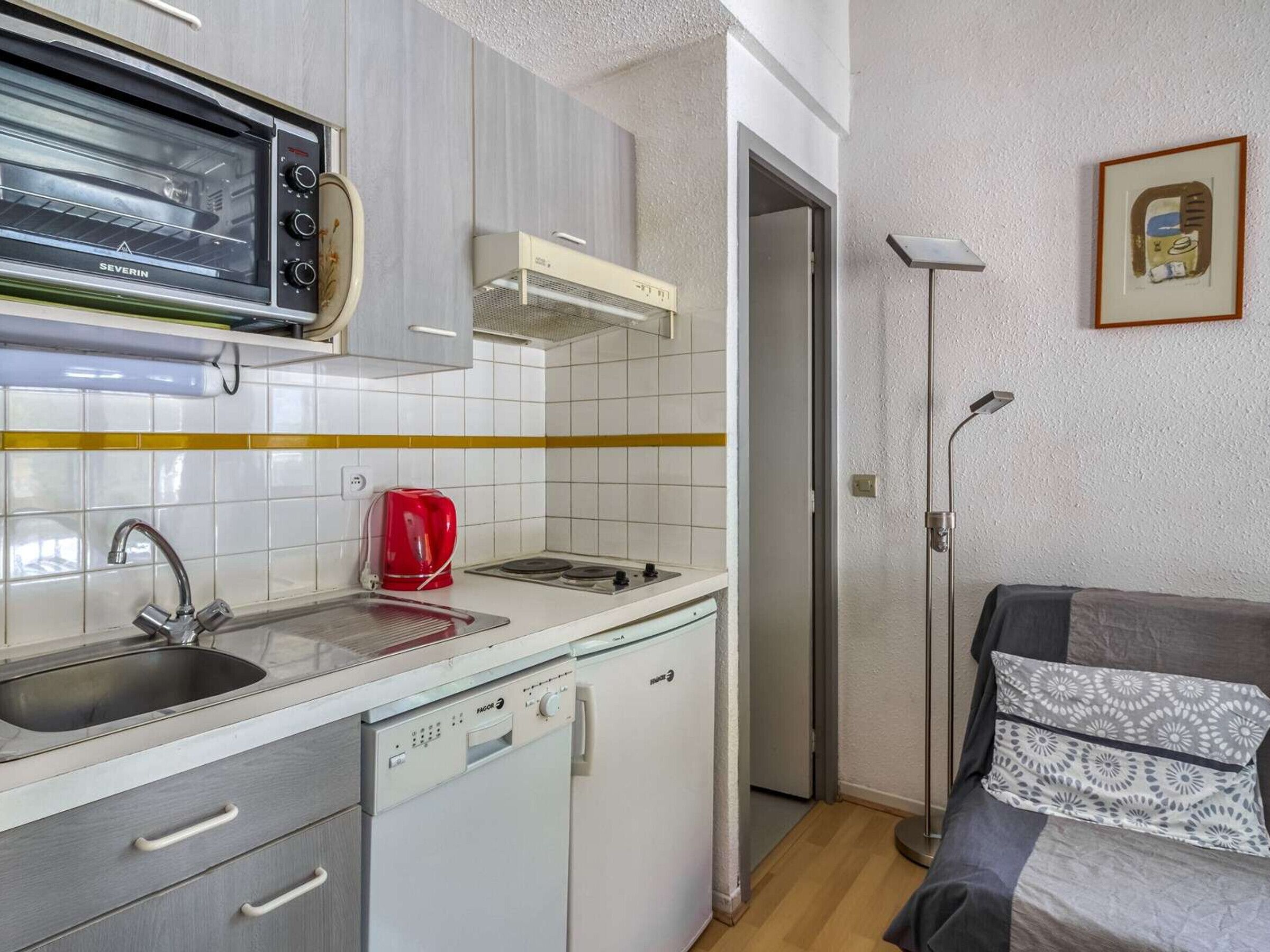 A compact kitchen with a built-in oven, a coffee maker, and a dishwasher.