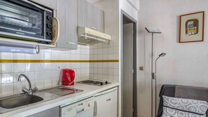 Una cucina compatta con forno a incasso, macchina del caffè e lavastoviglie.