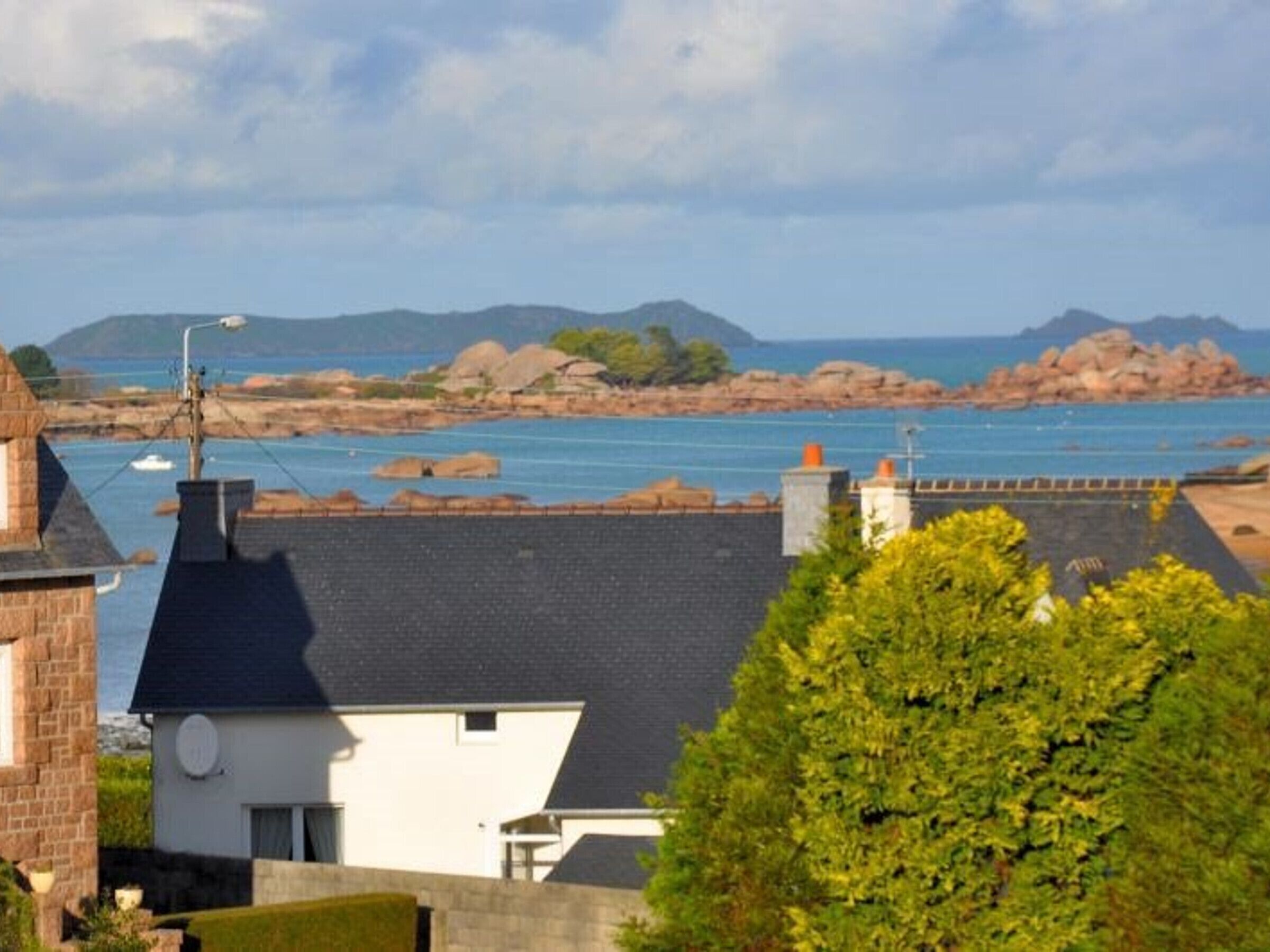 Un bâtiment situé sur la côte, doté d’un toit sombre, de murs blancs et d’une cheminée bien visible.