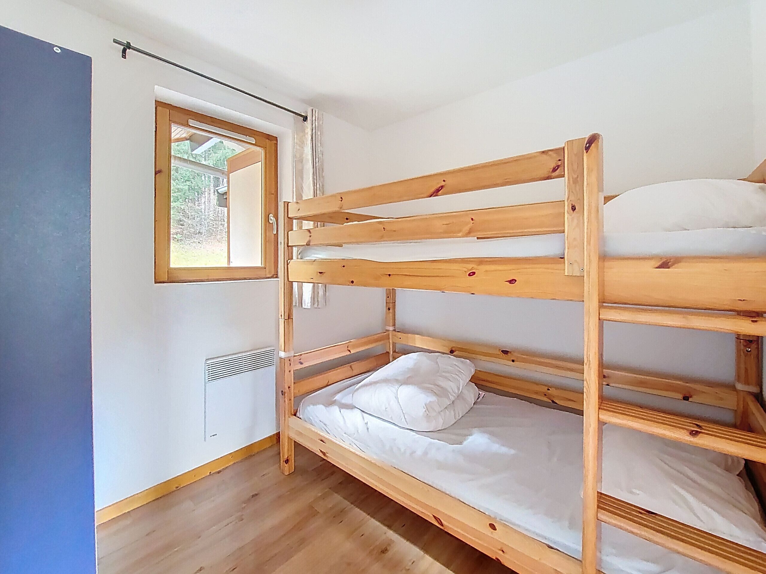 Ein Stockbett mit Fenster, Holzwänden und Lüftung.