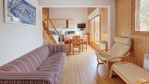 A cozy interior with a striped sofa, a wooden chair, and a dining area with a table and chairs.